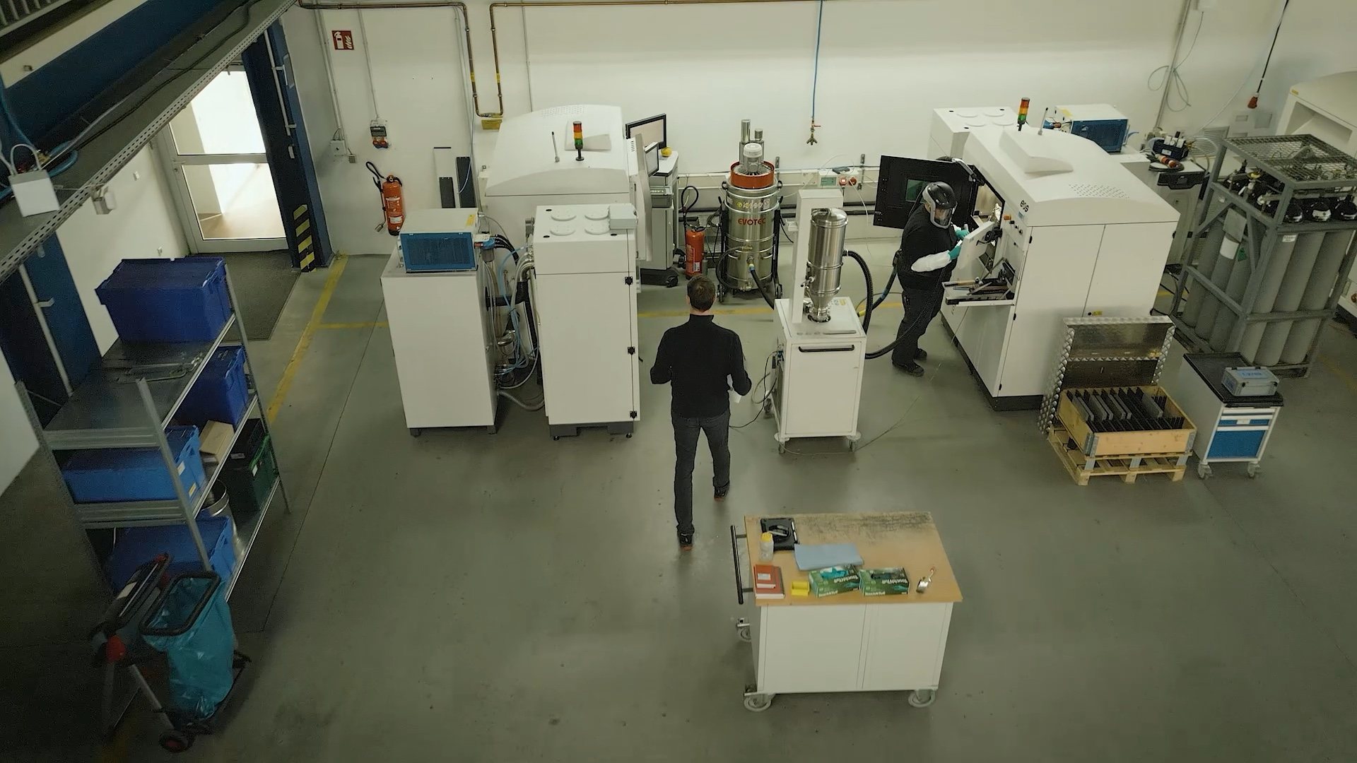 Overhead view of the LPBF shop floor with printers, gas supply and a depowdering station