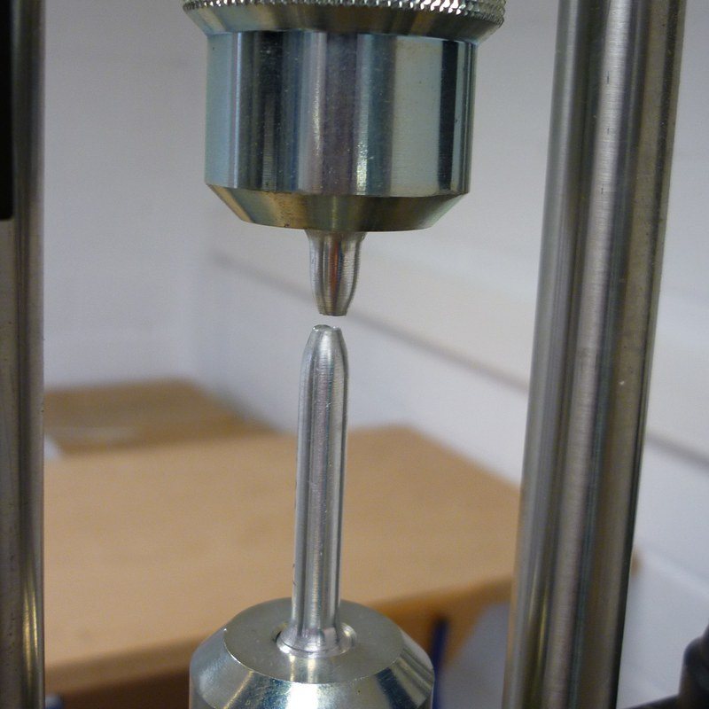 Fractured round tensile specimen between the grips of a tensile testing machine