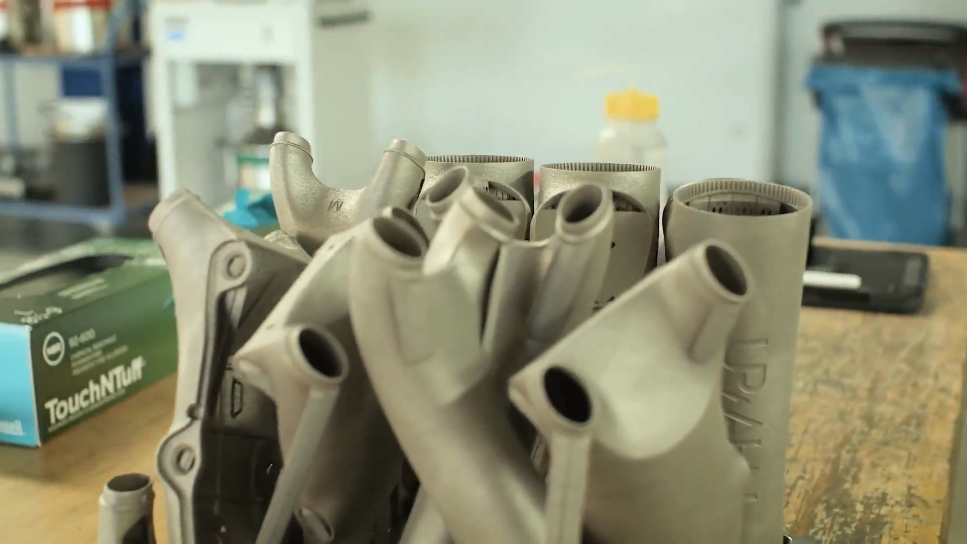 A batch of identical LPBF-printed metal frame parts, as built, on the workbench